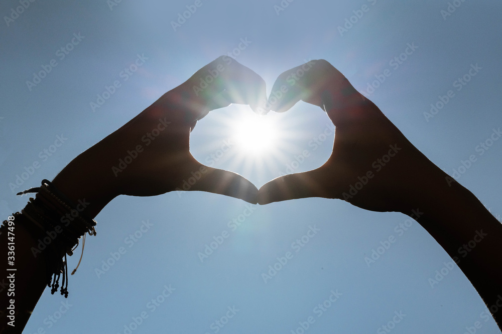 Fototapeta premium 2 hands that form a heart around the sun