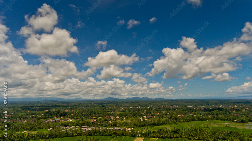 Fluffy white clouds in the blue sky over the green jungle. Aerial view, Bali, Indonesia.