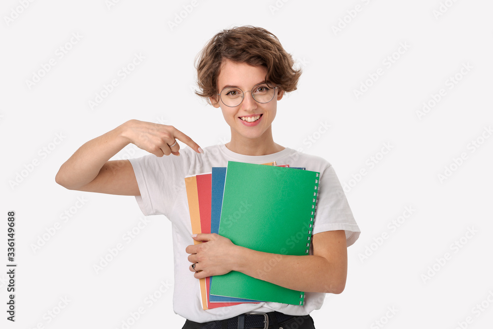 Female student in a white shirt and eyeglasses pointing at colorful folders Female student in a white shirt and eyeglasses pointing at colorful folders