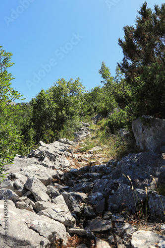 Forgotten stone road in a secluded part of Gradac, Split-Dalmatia County, Croatia. Dangerous path for settlers. Countryside in Hrvatska. Sunny day with blue sky. Ideal trip without people