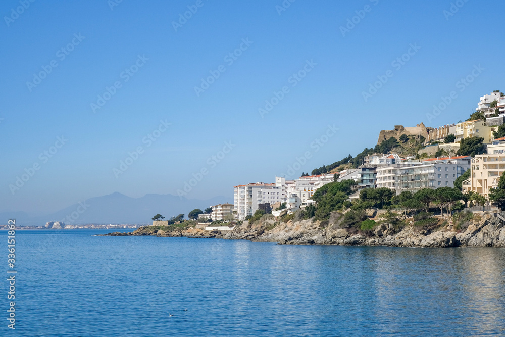 View on the wonderful resort town, Spain. Classic Spanish white houses with red tile roofs on mountains. Mediterranean resort city on sunny day, calm blue sea. Reflection of buildings on sea water. View on the wonderful resort town, Spain. Classic Spanish white houses with red tile roofs on mountains. Mediterranean resort city on sunny day, calm blue sea. Reflection of buildings on sea water.