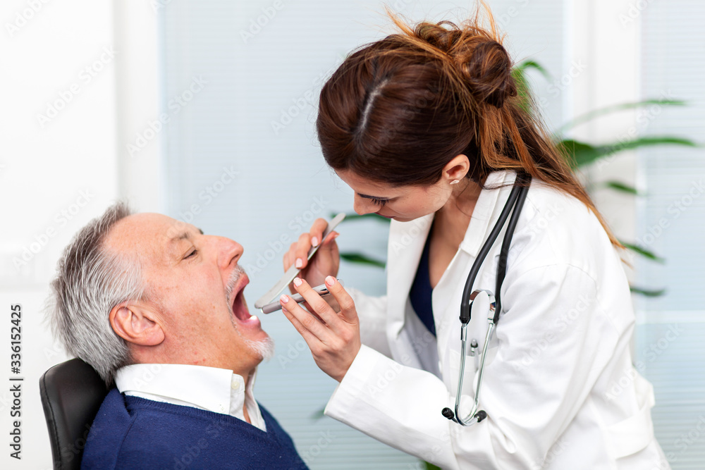 Obraz premium Female doctor visiting a patient by checking his throat