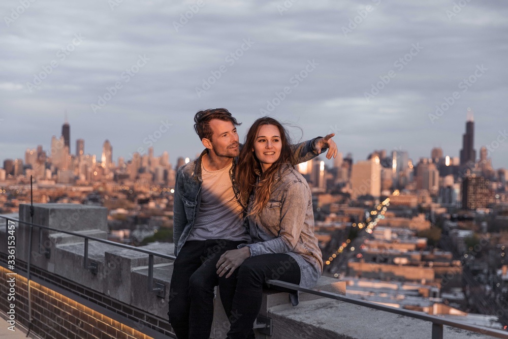 Naklejka premium Happy Couple sits on rooftop overlooking Chicago