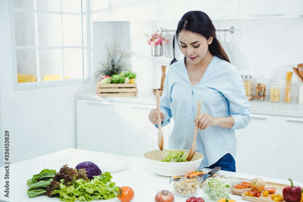 Woman is making fresh salad in the kitchen.