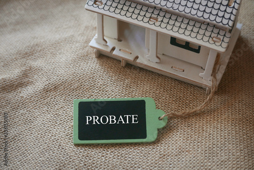A toy wooden house on a rugs with a wooden tag written with word Probate. photo