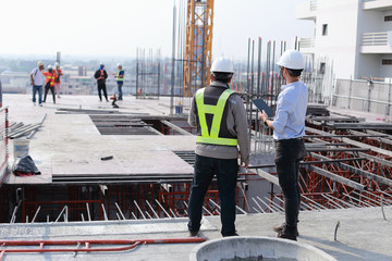 Two engineers work on the construction site. They are checking the progress of the work.