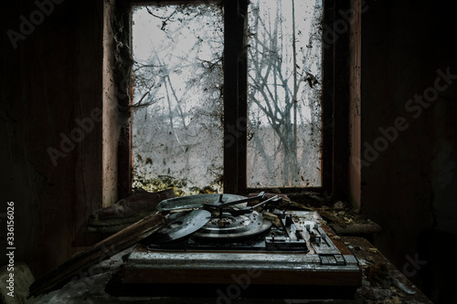 Old record player by window in abandoned house