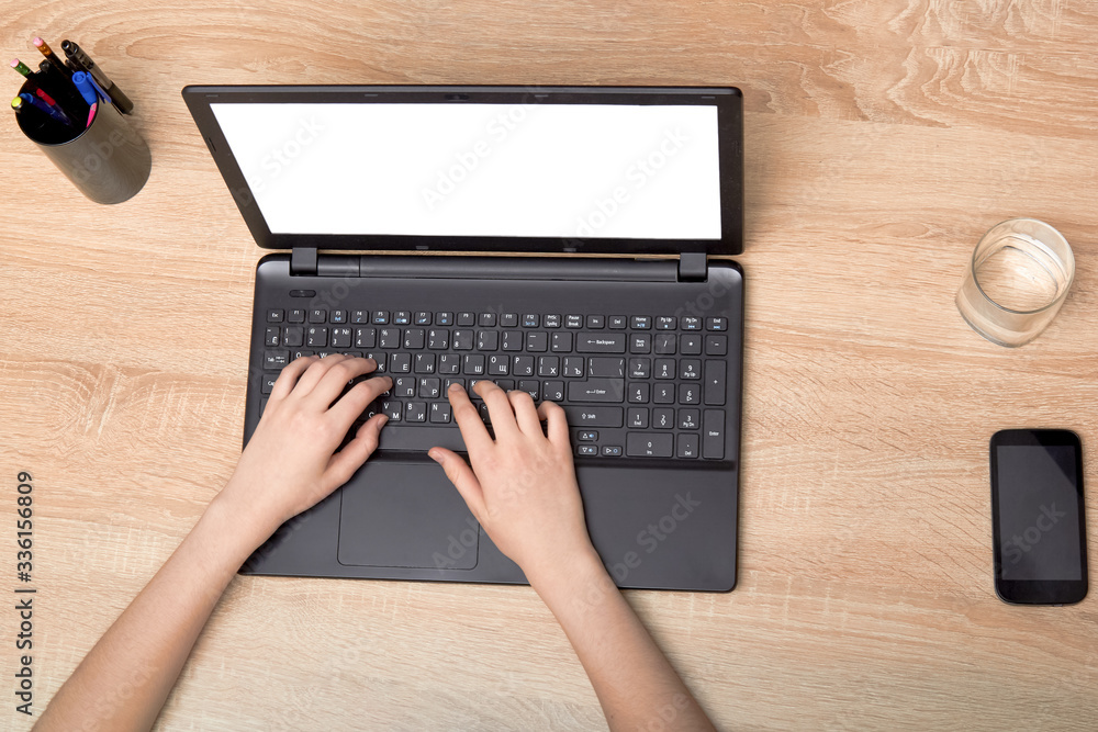 the girl's hands are typing on a laptop on the table the girl's hands are typing on a laptop on the table