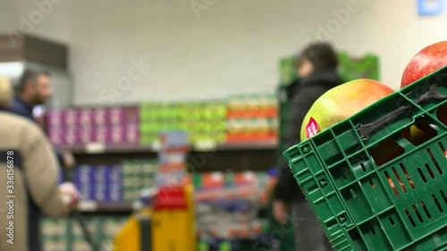 Tropical fruit mango in plastic green box in supermarket while customers passing by, close shot. photo