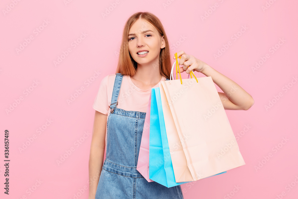 young stylish girl shopper holds shopping bags after shopping on an isolated pink background