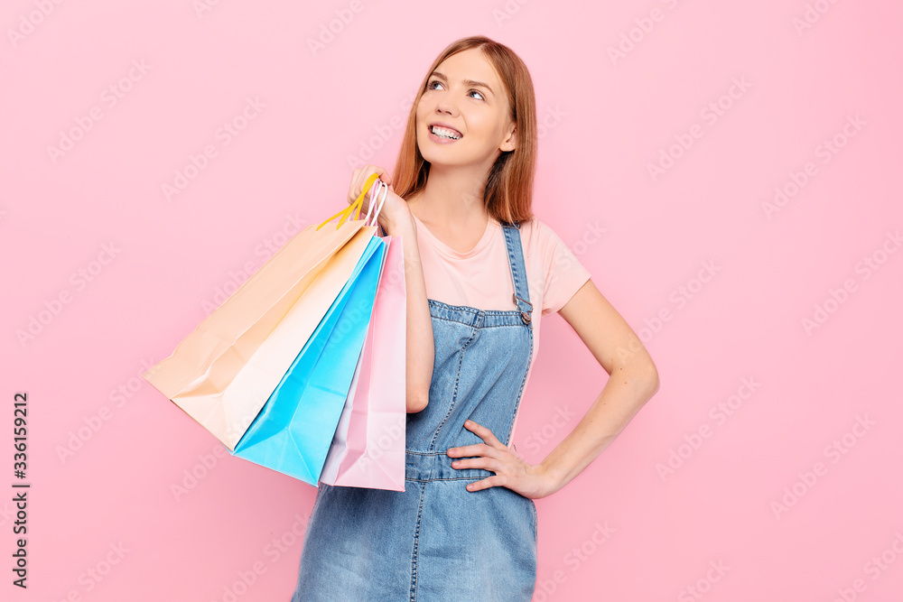 young stylish girl shopper holds shopping bags after shopping on an isolated pink background young stylish girl shopper holds shopping bags after shopping on an isolated pink background