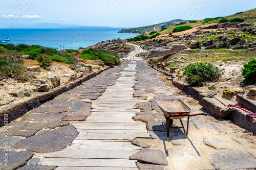 Wheel barrow and brooms on a downhill path in Tharros photo