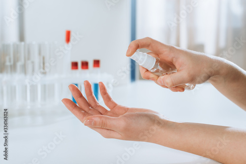 cropped view of doctor spraying antiseptic on hands near test tubes