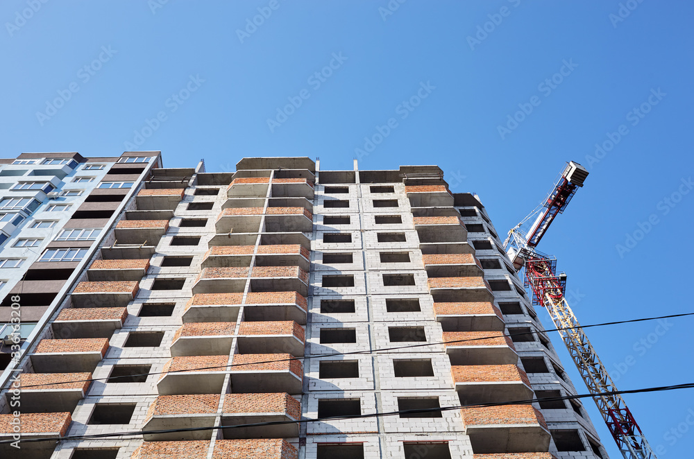 Fototapeta premium Tower crane building a house. Concrete building under construction. Construction site
