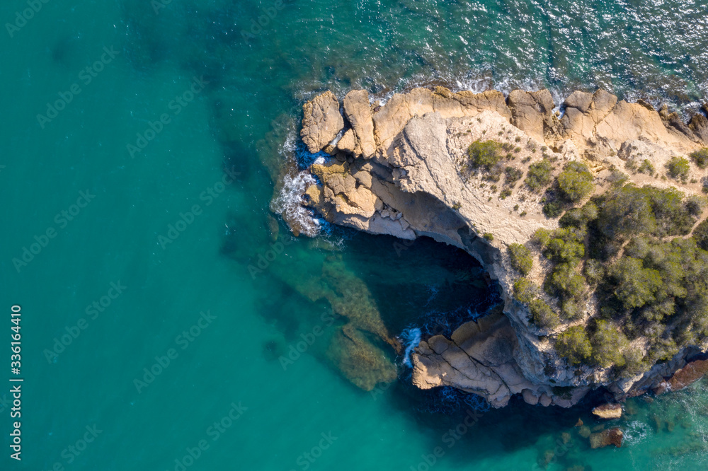 Aerial drone top-down view of calm turquoise water and rocks on the beautiful coast of Spain on the east side