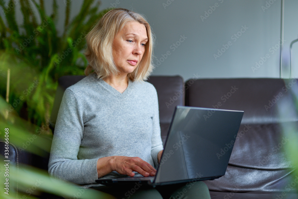 Woman on a sofa at home concentrating as she works on a laptop. Woman on a sofa at home concentrating as she works on a laptop.