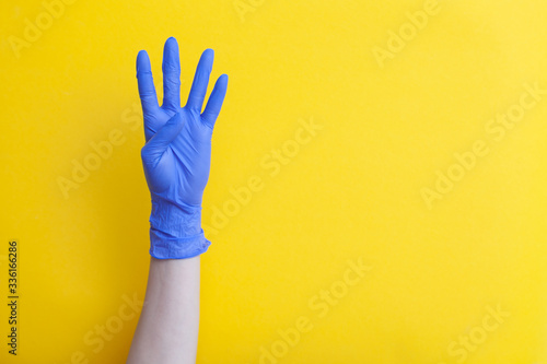 Doctor hand in medical lilac latex glove showing four fingers