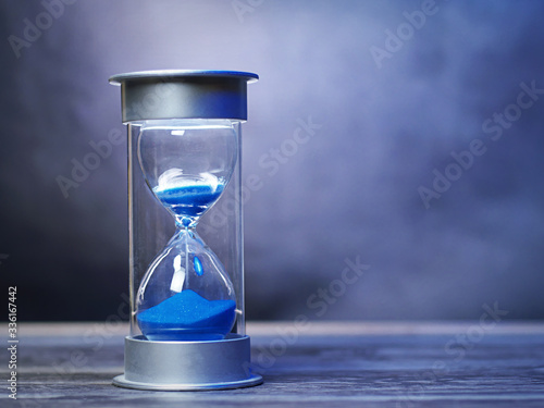 Vintage hour glass with blue sand. A symbol of time with copy space for titles