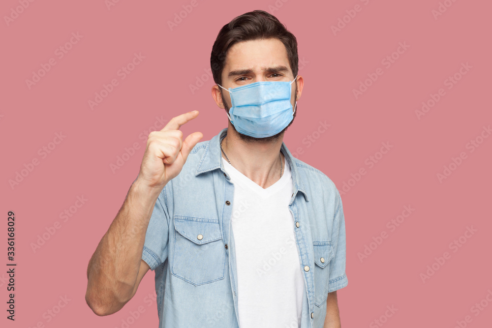 I need a few more. Portrait of young man with surgical medical mask in blue casual style shirt standing and looking at camera and begging for something. indoor studio shot, isolated on pink background I need a few more. Portrait of young man with surgical medical mask in blue casual style shirt standing and looking at camera and begging for something. indoor studio shot, isolated on pink background