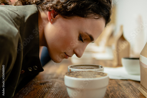 Mujer joven blanca oliendo tazas de café en una cata brasileña photo