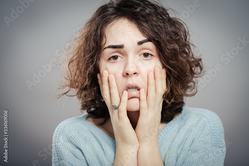 Fotografie Closeup portrait of young, upset, sad depressed, worried, troubled brunette woman holding her head with both hands, isolated