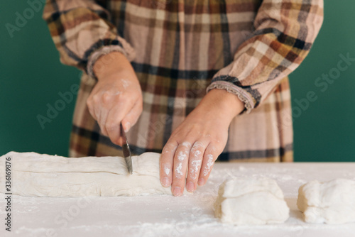 Woman cuts pieces of dough to prepare her handmade bread, homemade cooking.