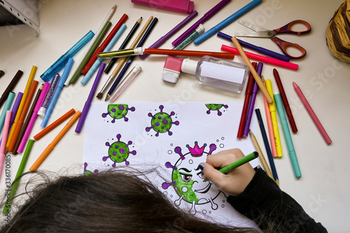 A child coloring virus painting on a table full of colors and a bottle of hydroalcoholic gel