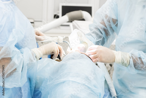 Close-up of the hands of a dentist and nurse surgeon over an operating room during a dental implant operation