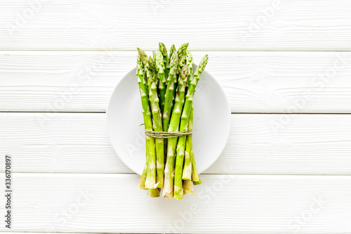 Asparagus. Banch of fresh steams on plate on white wooden background top-down copy space