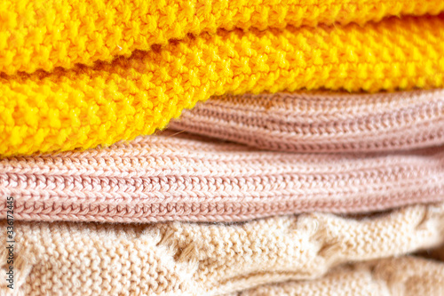 A stack of warm knitted things on a white table. Cozy clothes. Household concept. Close-up.