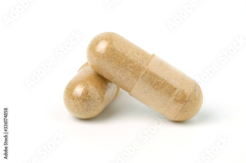 Two capsules of Finely ground dry Turmeric isolated on white background.