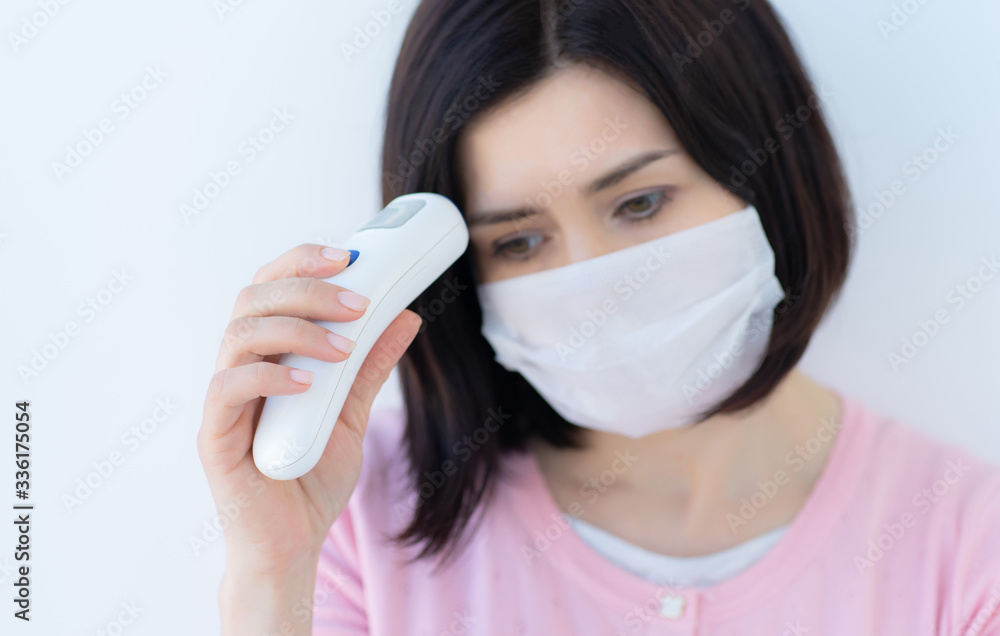 Woman in medical mask measuring temperature Woman in medical mask measuring temperature