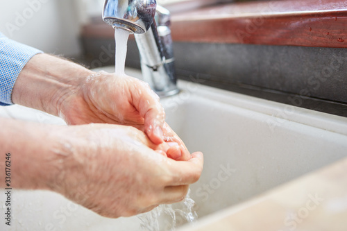 Senior beim Händewaschen mit Wasser und Seife
