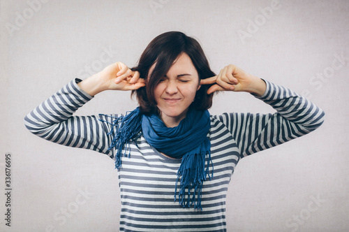 Young woman covering her ears over white background © aeroking