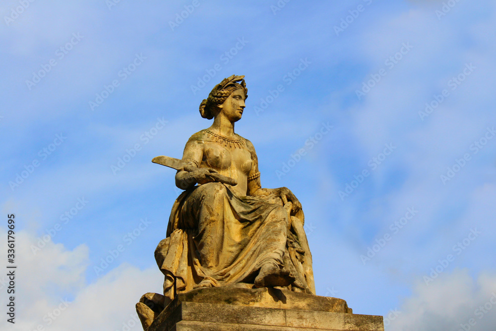 Stone figure of a woman mounted on the roof of an ancient building of the last century in Paris.