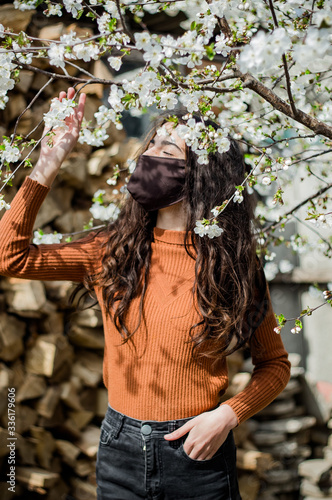 Girl looks in a mask respiratory at a tree with flowers