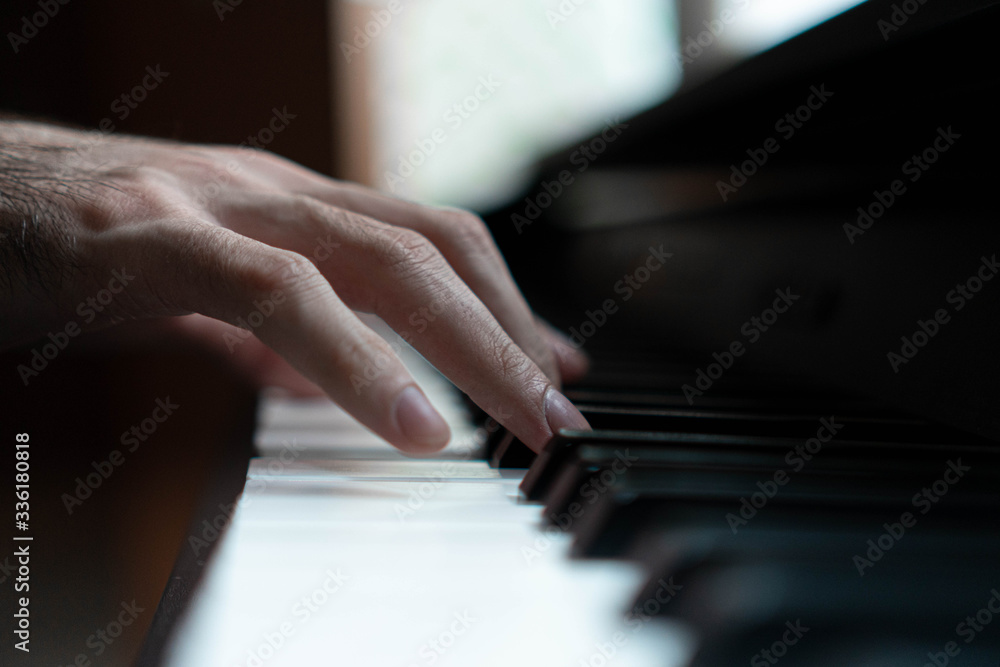 Fototapeta premium hands of a man playing the piano during the day, stylish photo