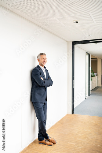 Wallpaper Mural Businessman corridor of office building, leaning on wall, with arms crossed Torontodigital.ca