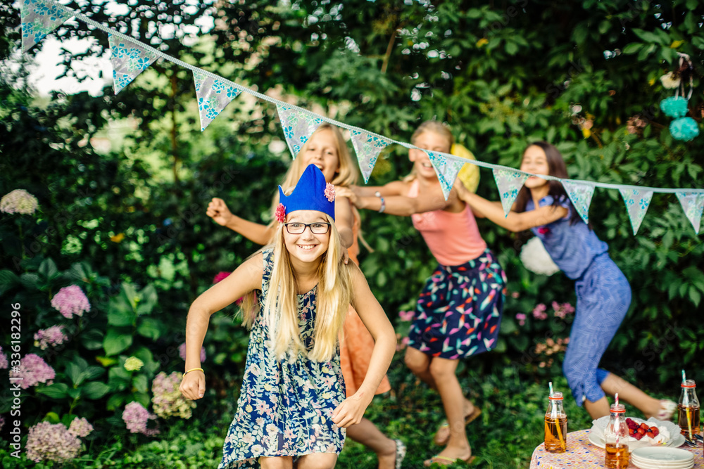 Foto de Happy girls doing a conga line on a birthday party outdoors do ...