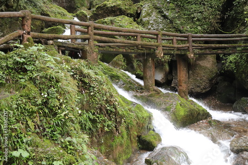  wooden bridge across a waterfall river in a mountain forest in Sichuan  China