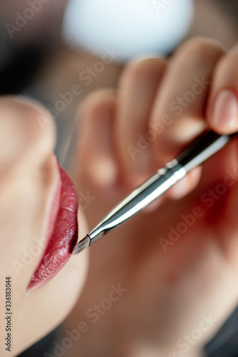 cropped view of makeup artist applying lipstick on woman