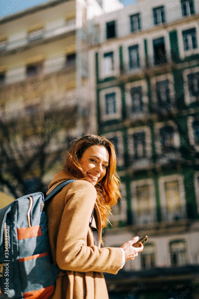 Portrait of happy young woman with backpack in the city, Lisbon, Portugal