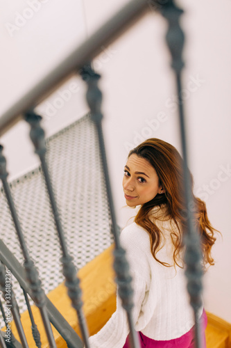 Portrait of young woman in staircase looking up photo