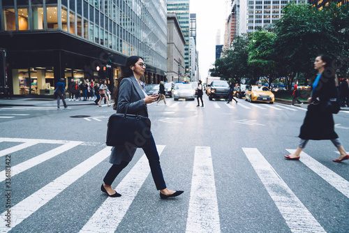 Photography Modern young female listening to music while crossing street