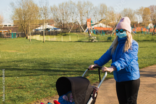 young mother at park with baby and pram during quarantine