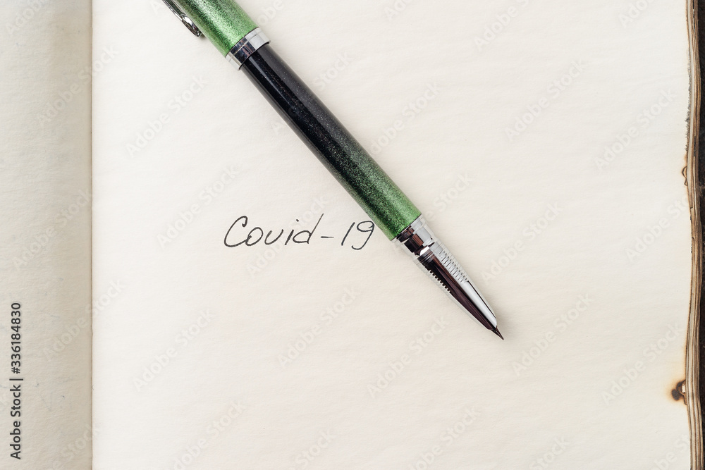 Covid-19 coronavirus inscription on a blank empty sheet of paper in a notebook. Nearby lies a pen. A lot of space for inscriptions and copyspace. Blank for inscriptions. Template for article or cover. Covid-19 coronavirus inscription on a blank empty sheet of paper in a notebook. Nearby lies a pen. A lot of space for inscriptions and copyspace. Blank for inscriptions. Template for article or cover.