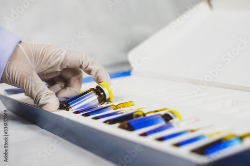 Tableau sur toile The doctor's hand is picking up the medicine vial bottle from box set,Coronavirus treatment concept,Covid-19