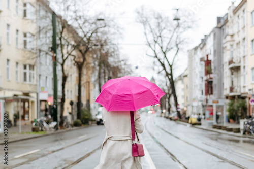 Fototapeta Naklejka Na Ścianę i Meble -  Rear view of a woman with pink umbrella walking on street