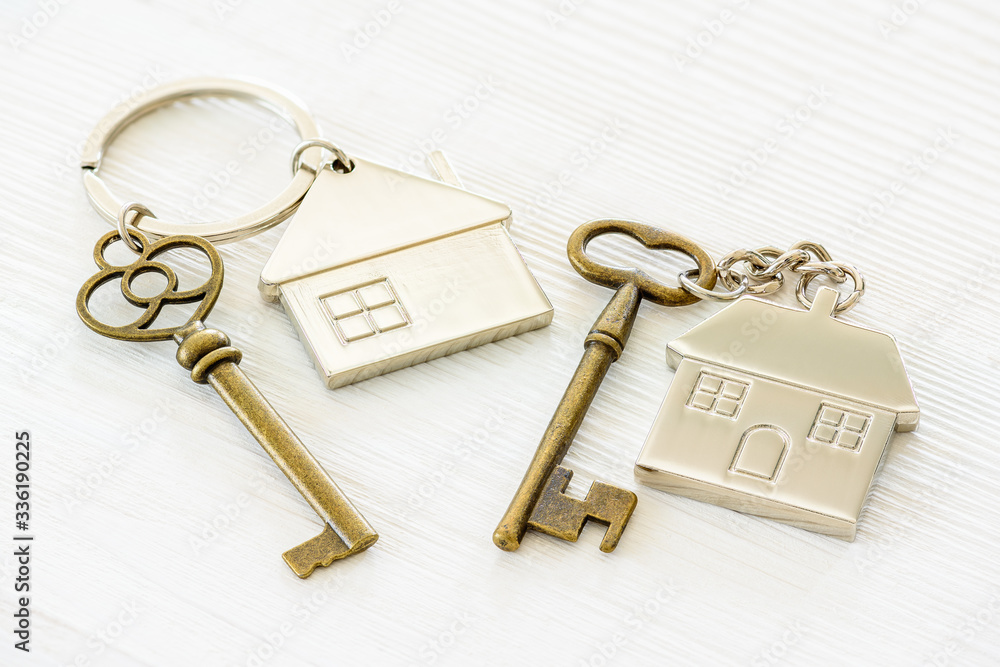 Two retro metallic / silver key and home key chain with keyring for homeowner to open the door. Security key for unlocking and access to a room or house or private residential asset. White background. Two retro metallic / silver key and home key chain with keyring for homeowner to open the door. Security key for unlocking and access to a room or house or private residential asset. White background.