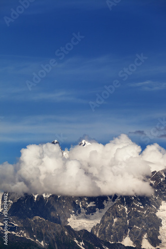 High rocky mountains with snow and glacier hidden in clouds
